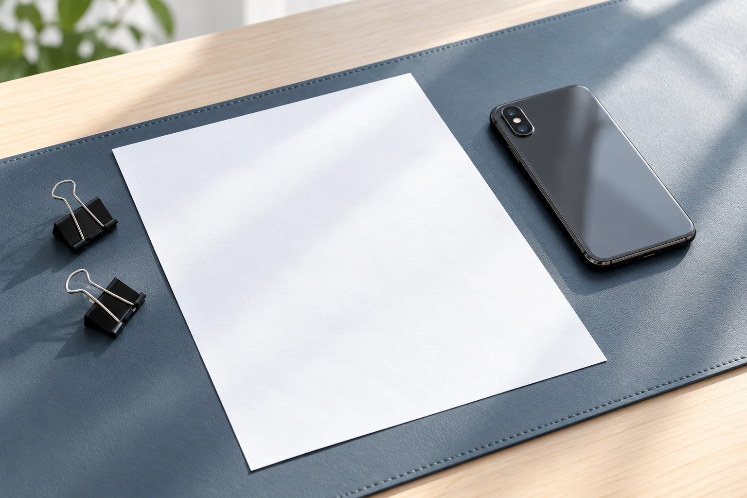 Flat blank sheet beside a phone on a contrasting desk mat.