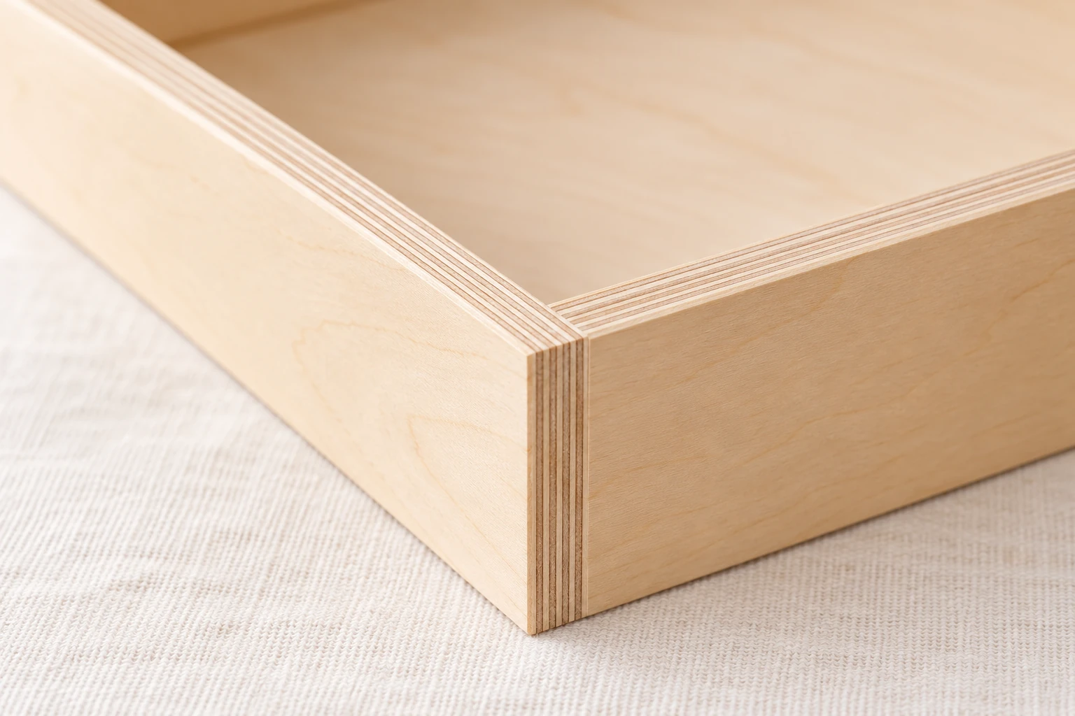 Layered edge of a plywood panel, showing the thin outer faces that need support while drilling.